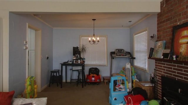 playroom featuring crown molding, a brick fireplace, a chandelier, and carpet