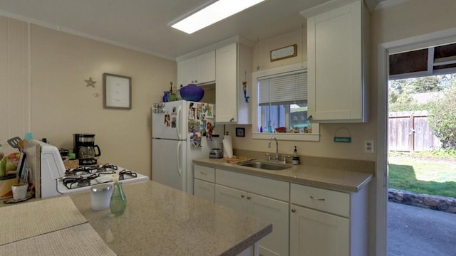 kitchen with light stone countertops, white cabinets, sink, and white fridge