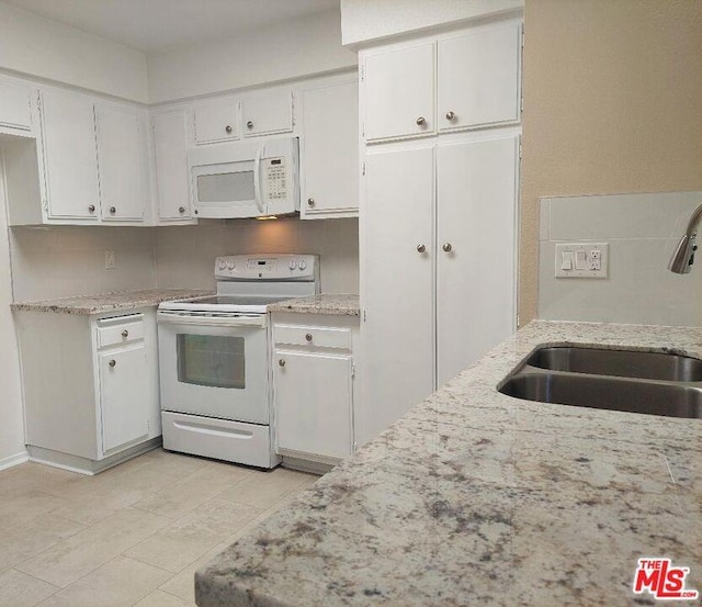 kitchen with white cabinets, light stone countertops, white appliances, and sink