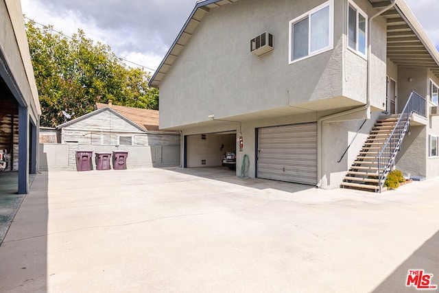 view of side of property with an AC wall unit and a garage