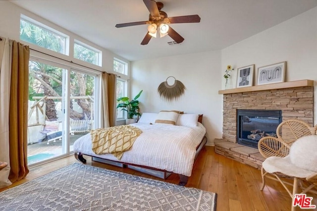 bedroom featuring a fireplace, light wood-type flooring, access to exterior, and ceiling fan