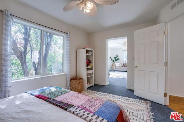 carpeted bedroom with multiple windows and ceiling fan