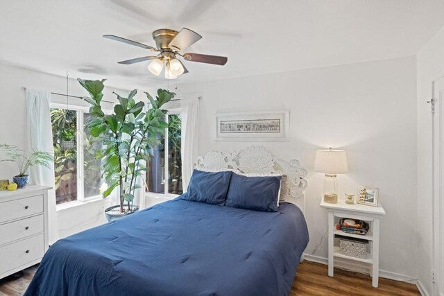 bedroom with multiple windows, dark hardwood / wood-style floors, and ceiling fan