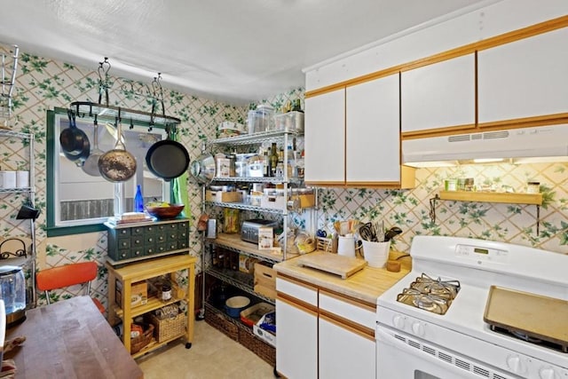 kitchen with white range oven, white cabinets, tasteful backsplash, and light tile floors