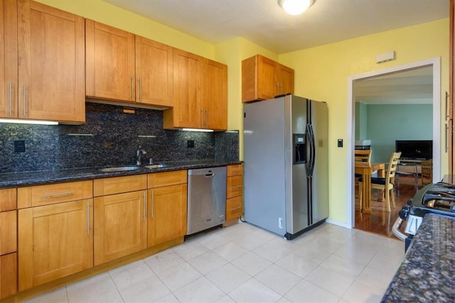 kitchen with stainless steel appliances, dark stone counters, tasteful backsplash, light wood-type flooring, and sink