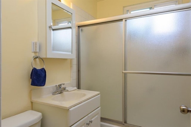 bathroom featuring an enclosed shower, vanity with extensive cabinet space, and toilet