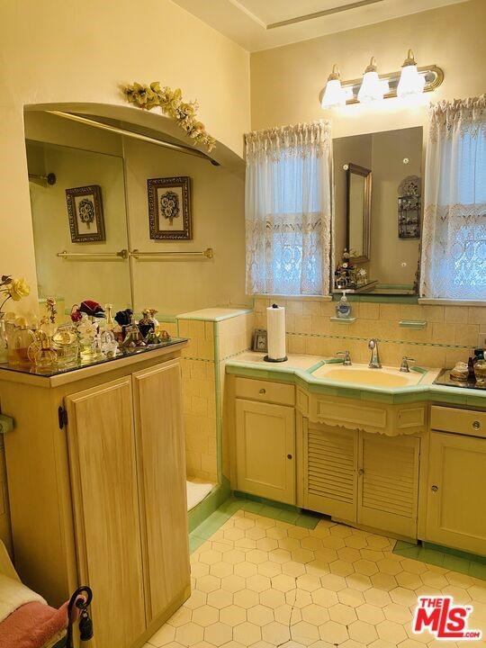 bathroom featuring tasteful backsplash, vanity, and tile flooring