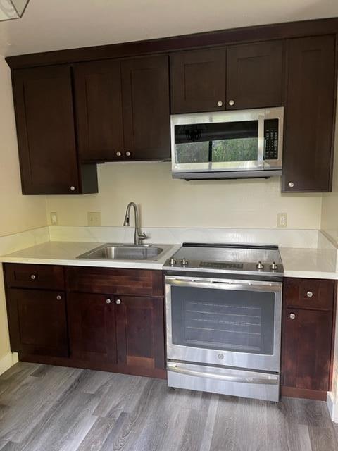 kitchen with appliances with stainless steel finishes, light wood-type flooring, and sink