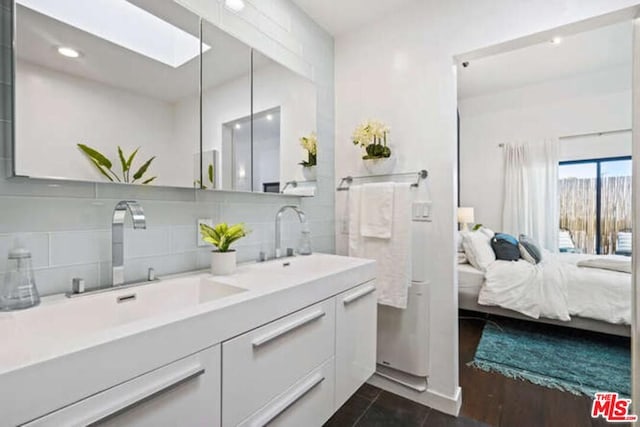 bathroom with double sink, tile flooring, oversized vanity, and tasteful backsplash