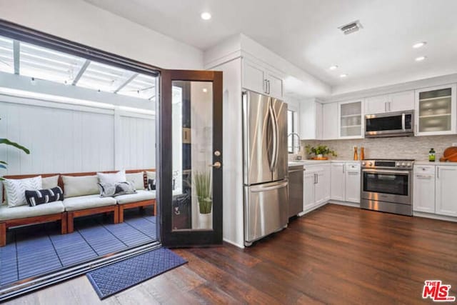 kitchen with white cabinetry, tasteful backsplash, dark wood-type flooring, and stainless steel appliances