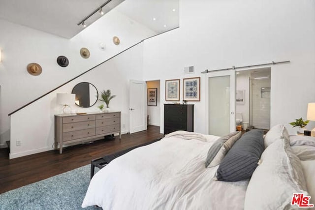 bedroom featuring high vaulted ceiling, dark hardwood / wood-style floors, ensuite bathroom, and rail lighting