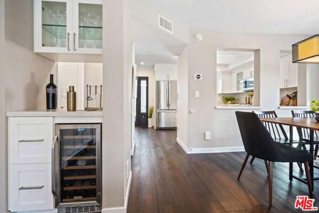 bar with beverage cooler, white cabinetry, dark hardwood / wood-style flooring, and stainless steel appliances