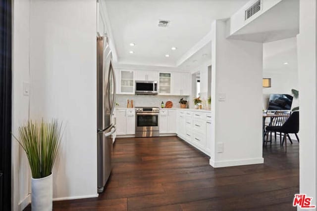 kitchen featuring white cabinetry, backsplash, dark hardwood / wood-style flooring, and stainless steel appliances