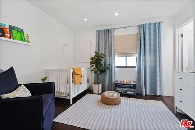 bedroom with dark hardwood / wood-style floors, radiator, and a crib