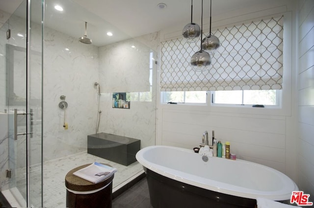 bathroom with shower with separate bathtub and tile walls