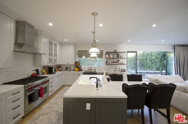 kitchen featuring wall chimney exhaust hood, a wealth of natural light, pendant lighting, and range with two ovens