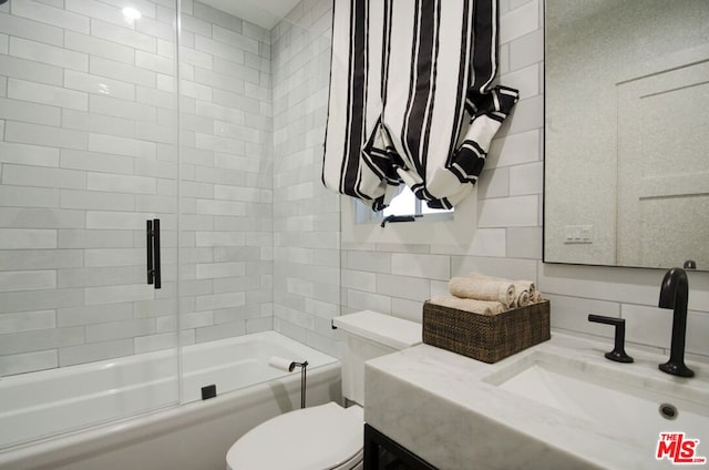 full bathroom with tile walls, shower / bath combination with glass door, tasteful backsplash, vanity, and toilet