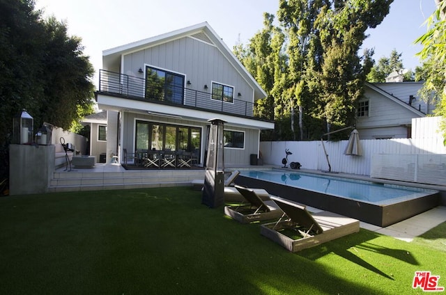 back of house with a balcony, a yard, a patio area, and a fenced in pool