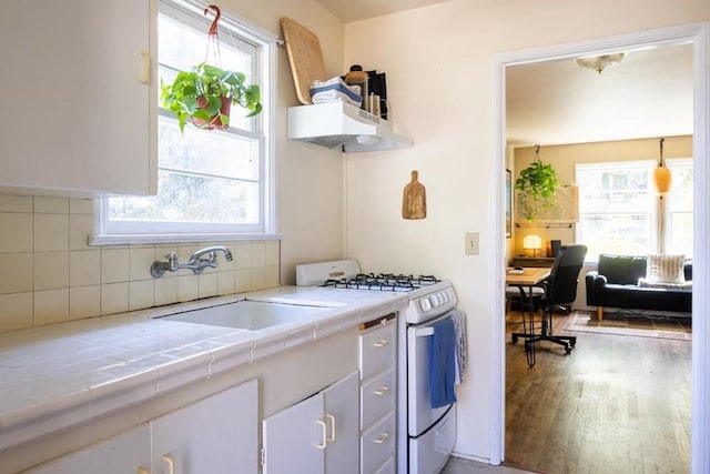 kitchen featuring sink, plenty of natural light, white gas range, tile countertops, and hardwood / wood-style flooring