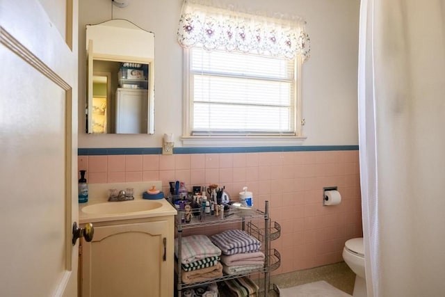 bathroom with toilet, tasteful backsplash, vanity, and tile walls