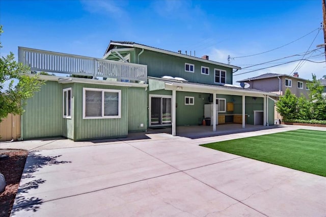 back of property featuring a balcony, a patio area, and a yard