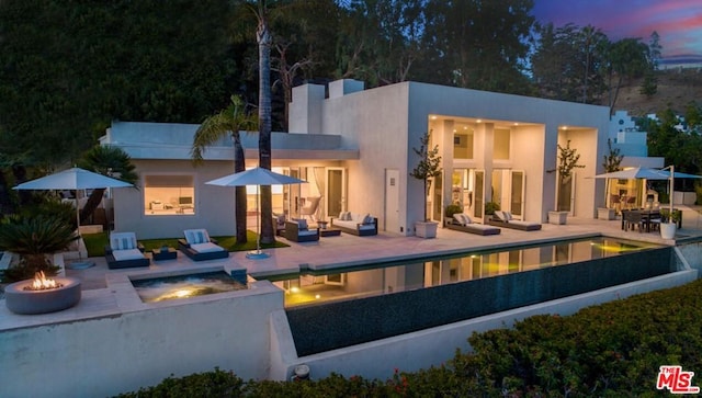 back house at dusk with an outdoor fire pit and a patio area