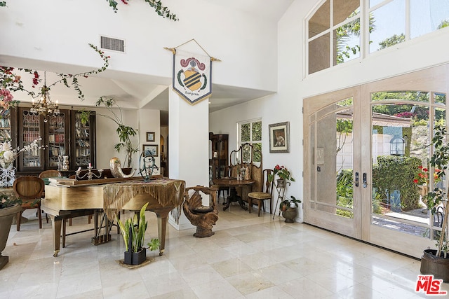 interior space featuring french doors, a notable chandelier, and a towering ceiling