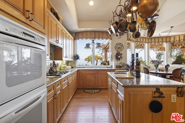 kitchen featuring double oven, a wealth of natural light, a kitchen island, and hardwood / wood-style floors