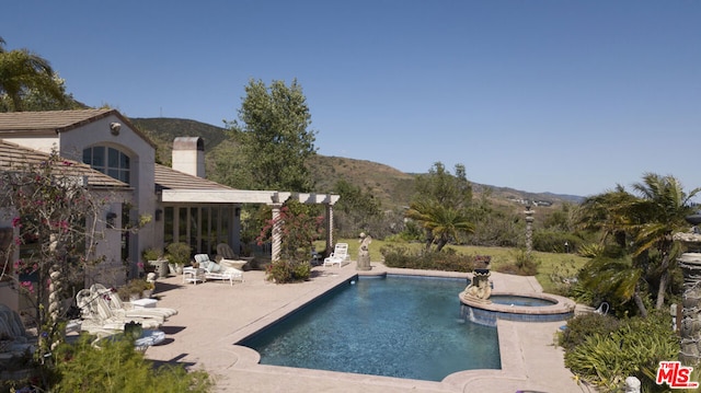 view of pool with a patio, an in ground hot tub, and a mountain view