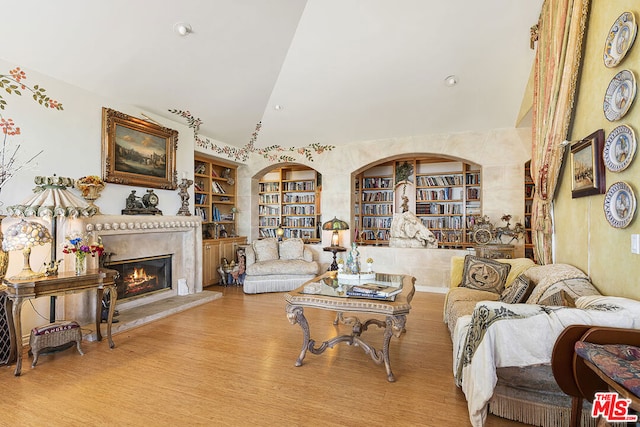 living room featuring vaulted ceiling, built in shelves, and light hardwood / wood-style floors