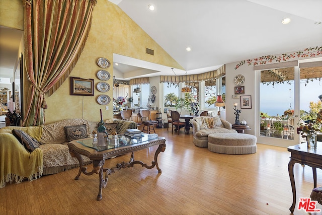 living room with light hardwood / wood-style floors and high vaulted ceiling