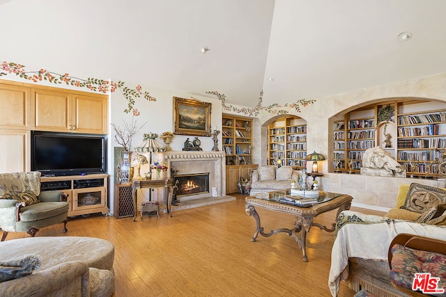 living room with lofted ceiling, light wood-type flooring, and built in features