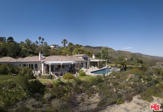 rear view of house featuring a patio, a mountain view, and a fenced in pool