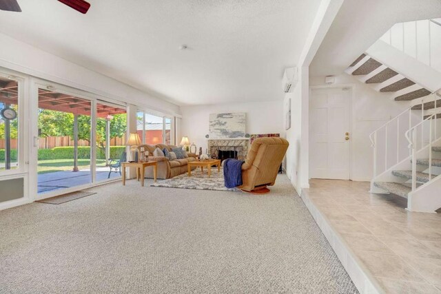 sitting room featuring ceiling fan, a wall unit AC, a fireplace, and light colored carpet