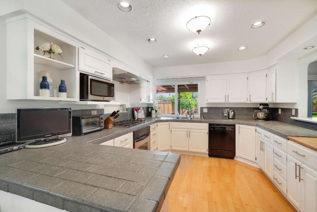 kitchen featuring tasteful backsplash, appliances with stainless steel finishes, light hardwood / wood-style floors, sink, and white cabinets