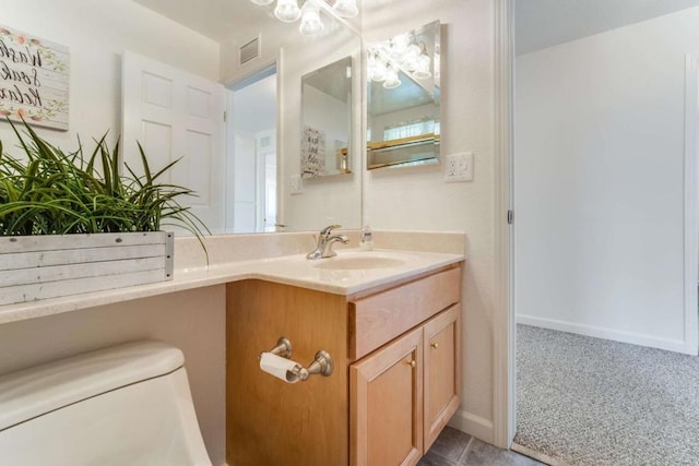 bathroom with toilet, vanity, and tile patterned flooring