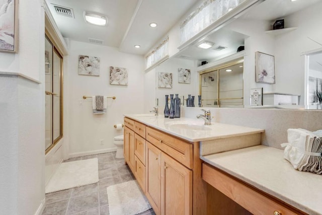 full bathroom with combined bath / shower with glass door, toilet, vanity, and tile patterned flooring