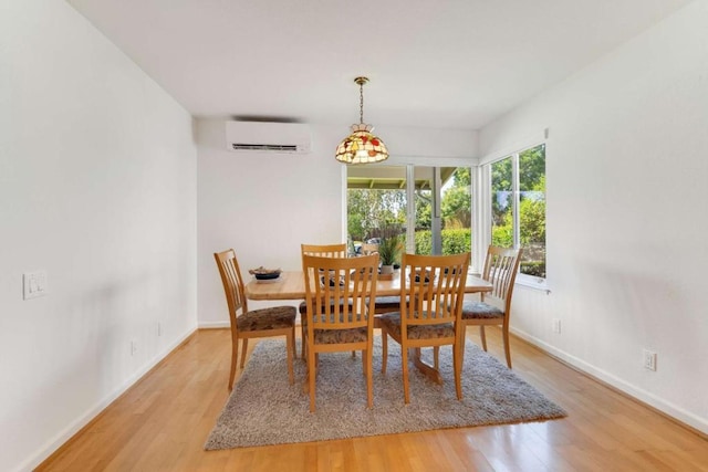 dining space with a wall unit AC and light hardwood / wood-style floors