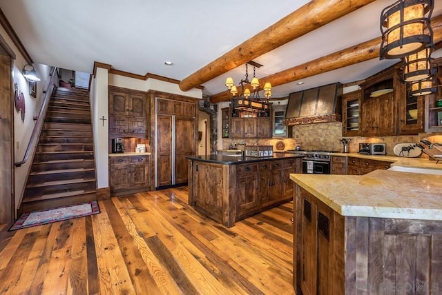 kitchen with a notable chandelier, light hardwood / wood-style floors, wall chimney range hood, tasteful backsplash, and pendant lighting