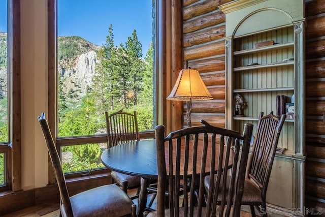 dining area featuring a healthy amount of sunlight, rustic walls, and a mountain view