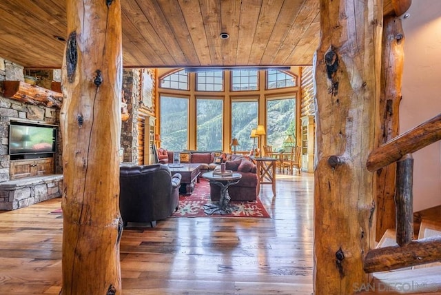 living room with a high ceiling, light hardwood / wood-style flooring, wood ceiling, and a fireplace