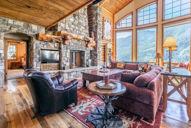 living room with a stone fireplace, light hardwood / wood-style floors, wooden ceiling, and a wealth of natural light