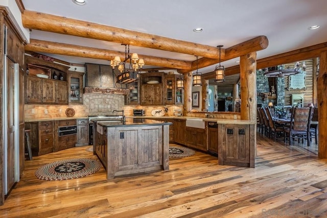 kitchen featuring decorative light fixtures, light hardwood / wood-style flooring, beam ceiling, and an island with sink