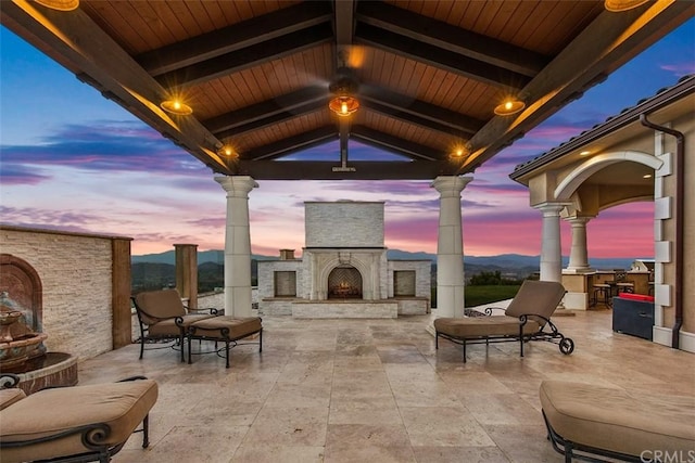 patio terrace at dusk featuring a gazebo and an outdoor stone fireplace