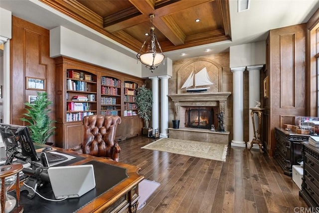 interior space featuring a tile fireplace, coffered ceiling, dark hardwood / wood-style floors, and ornate columns