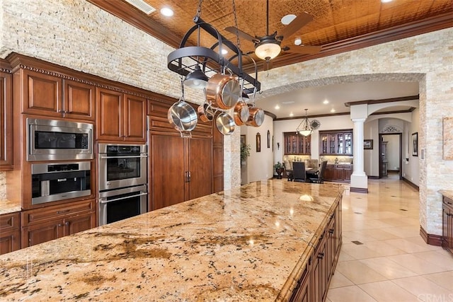 kitchen featuring light stone countertops, ceiling fan, decorative columns, light tile floors, and built in appliances