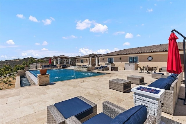 view of pool featuring an outdoor living space with a fire pit, pool water feature, and a patio area