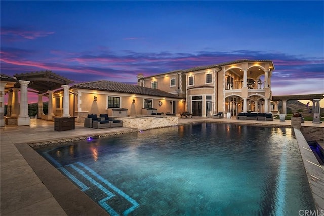 pool at dusk featuring a patio and an outdoor living space