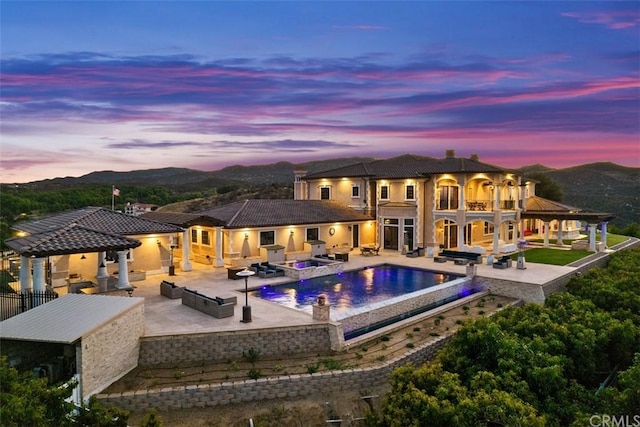 pool at dusk featuring a gazebo, an outdoor hangout area, exterior kitchen, and a patio area