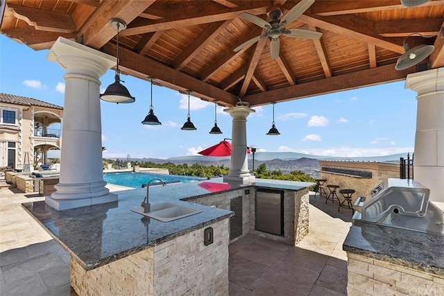 view of patio featuring area for grilling, a mountain view, a gazebo, ceiling fan, and sink